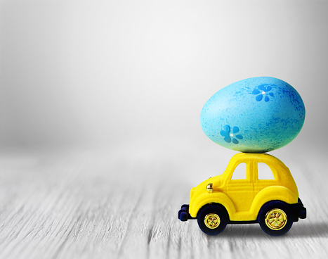 Easter egg and toy car on grey background, happy easter day concept.