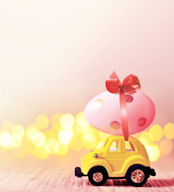 istock Easter egg and toy car on light bokeh background, happy easter day concept 1131634560