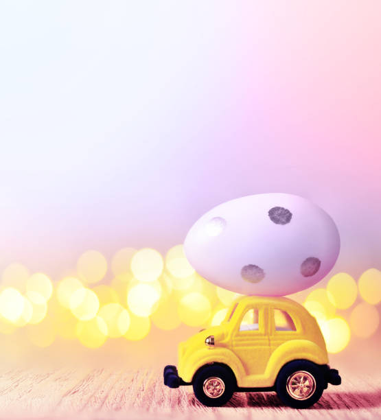istock Easter egg and toy car on light bokeh background, happy easter day concept 1131634582