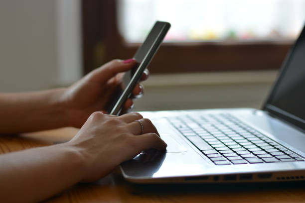 istock a woman working with the computer and with the phone at home 1131634826