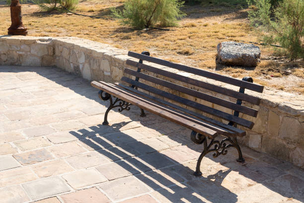 istock Front view of wooden maroon bench on sidewalk in park. 1131636347