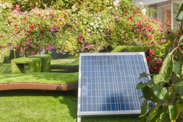 panell solar na parte traseira ou na jarda dianteira da casa com árvores e floresce o dia ensolarado morno da mola ou de verão. - chair grass flower bed nobody - fotografias e filmes do acervo