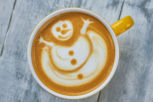 Latte art snowman. Coffee cup top view.