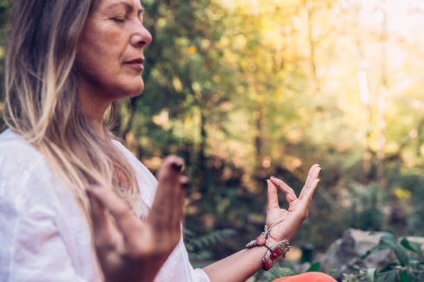 mujer madura meditando en el bosque - women yoga yoga class mature adult fotografías e imágenes de stock