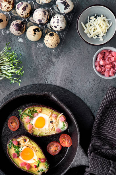 istock Keto diet dish: Avocado boats with ham cubes, quail eggs, cheese, ingredients around 1131652644