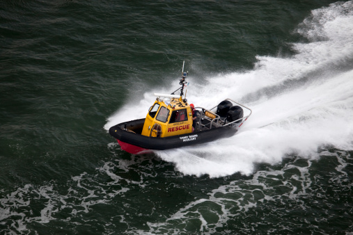 A small coast guard rescue boat racing through the sea.
