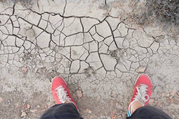 istock man standing on dry cracked soil 1131657157