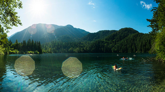 Panoramic shot of People swimming at Lake of the Woods in the beautiful wilderness landscape of the Canadian Rockies of British Columbia, Canada. Multiple files stitched.