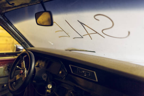 Inside view of old broken car interior with dusty vehicle dashboard, back mirror, driving steering wheel and dirty wind screen with title SALE written outside. Concept of sale pre-owned cars on the repair parts vista interior del viejo interior roto del coche con el tablero polvoriento del vehículo, espejo trasero, conduciendo el volante y la pantalla sucia del viento con el título venta escrito afuera. concepto de venta de coches seminuevo en las piezas de rep