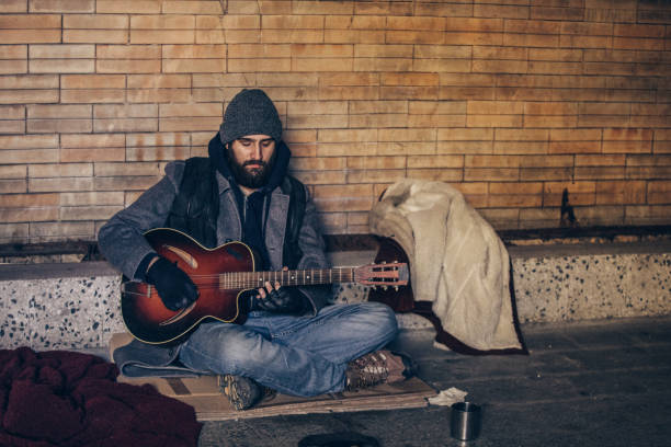 istock Homeless man playing guitar in underpass tunnel 1131659107