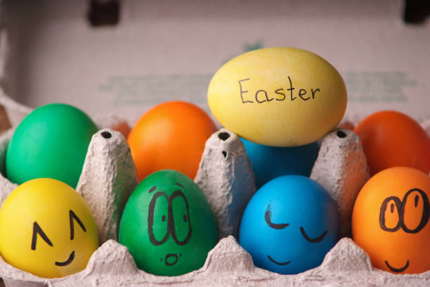 istock Colorful Easter eggs with painted face in egg carton box on wooden background. Writer on egg Easter 1131665726