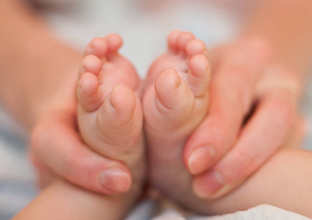 Mother gently hold baby legs in hand  dearness stock pictures, royalty-free photos & images