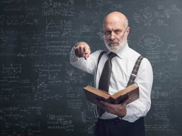 istock Academic professor holding a book and pointing 1131673136