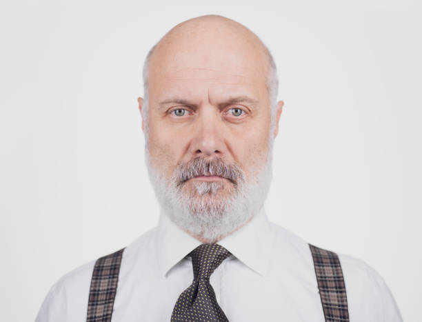 Serious mature businessman standing and posing, he is staring at the camera with confident attitude