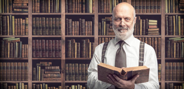 istock Academic professor in the library holding a book 1131673575