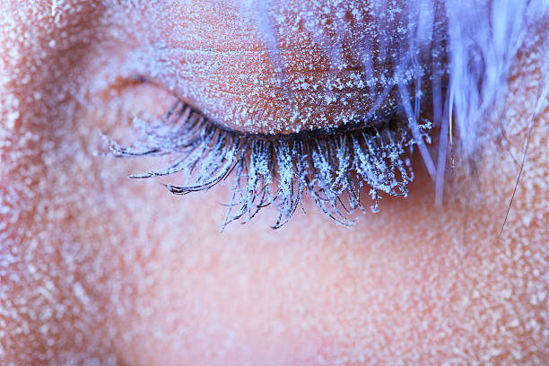 Close-up of woman's tinted closed eye with frost frozen on Frozen woman's eye covered in frost. Close-up shot of left eye with blue lashes frost face stock pictures, royalty-free photos & images