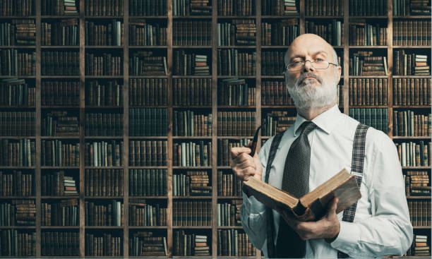 istock Academic professor in the library holding a book 1131675494