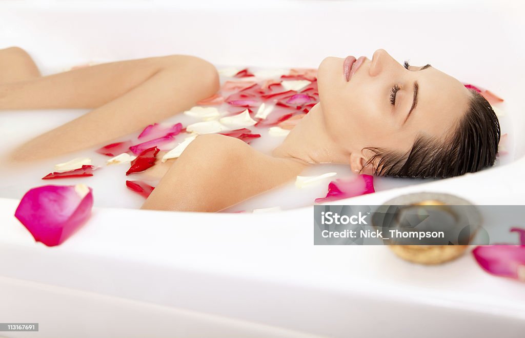 Attractive naked girl enjoys a milk bath with rose petals  Adult Stock Photo