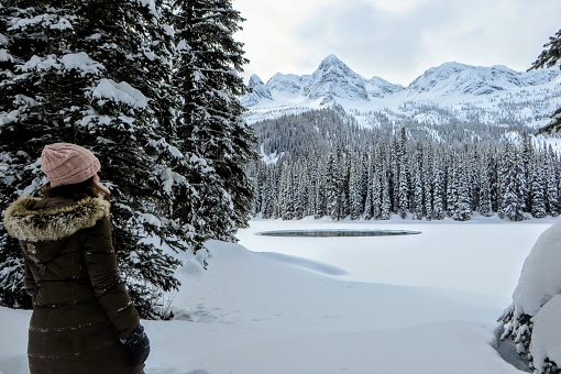 A young woman admiring the snowy views of Island Lake in Fernie, British Columbia, Canada.  The majestic winter background is an absolutely beautiful place to go snowshoeing with fresh fallen snow.