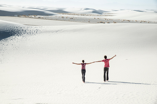Happy couple walking hand in hand at the White Sands National Monument, New Mexico, USA. Freedom on sand dunes.
