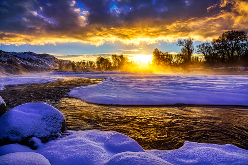 Sunrise Landscape in Winter Eagle River - Tributary river of the Colorado River scenic sunrise with dramatic warm light and mist rising. Snow and ice frozen scenic winter wonderland.