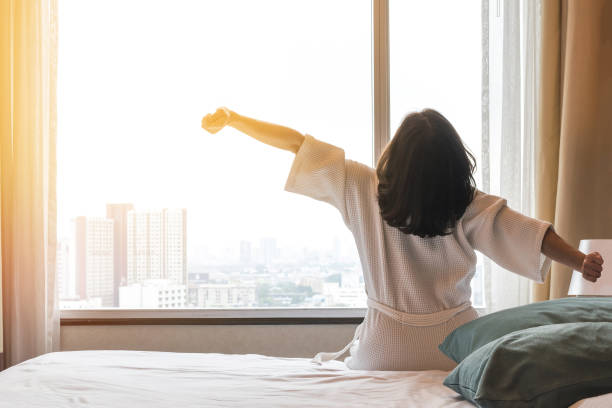 Simple city lifestyle happy woman waking up in the morning taking some rest relaxing in luxury comfy city hotel room Simple city lifestyle happy woman waking up in the morning taking some rest relaxing in luxury comfy city hotel room person waking up stock pictures, royalty-free photos & images