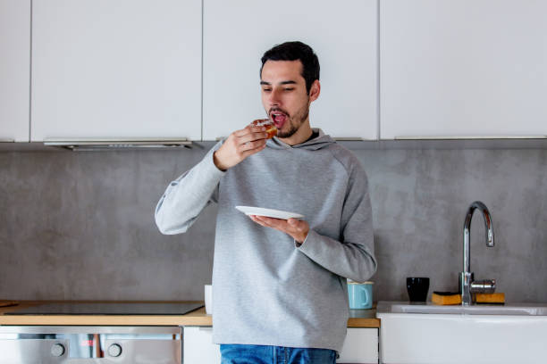 istock Man eating donut on breakfast at kitchen 1131687060