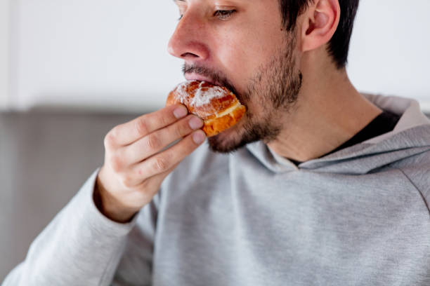 istock Man eating donut on breakfast at kitchen 1131687067