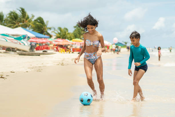 children playing soccer on on beach - beach football imagens e fotografias de stock