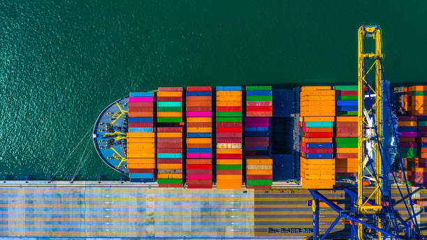 контейнер грузовое судно с рабочим краном моста разряда на контейнерном терминале, воздушный верхний вид контейнеровоза в глубоководном п - циндао стоковые фото и изображения