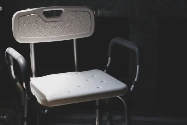 Photo of Plastic bathing chair for elder or disabled people showering put in dark letting light come from left side