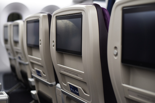 Row of airplane seatbacks with flat screens.