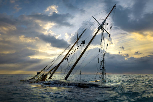 naufrage sur la plage. bateau échoué sur le rivage. navire submergé par les vagues au coucher du soleil. - sunken photos et images de collection