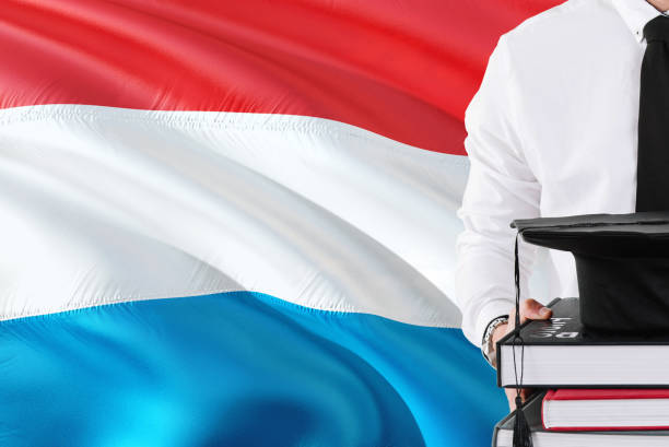istock Successful Luxembourger student education concept. Holding books and graduation cap over Luxembourg flag background. 1131724433
