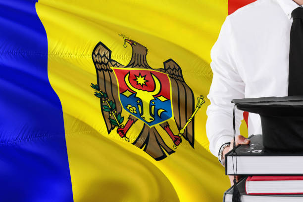 Successful Moldovan student education concept. Holding books and graduation cap over Moldova flag background.