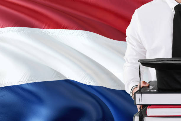 istock Successful Dutch student education concept. Holding books and graduation cap over Netherlands flag background. 1131724463