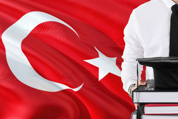 istock Successful Turkish student education concept. Holding books and graduation cap over Turkey flag background. 1131724554