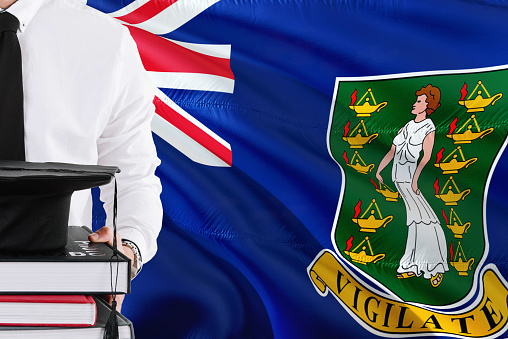 Successful student education concept. Holding books and graduation cap over British Virgin Islands flag background.