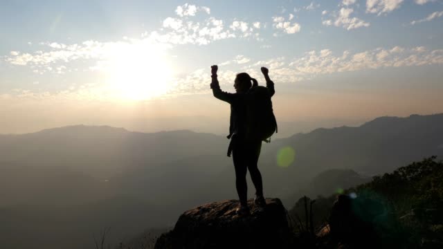 Woman hiking to the Mountain peak and hands up on head celebrating successful , SLOW MOTION