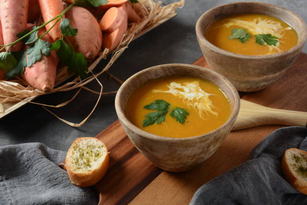 Sweet potato and carrot soup Sweet potato and carrot soup served with sour cream in wooden bowl. Orange vegetable soup concept. Vegan food cream soup stock pictures, royalty-free photos & images