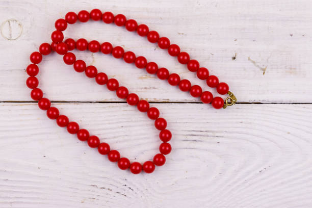 Shiny red coral beads on wooden background. Close-up.