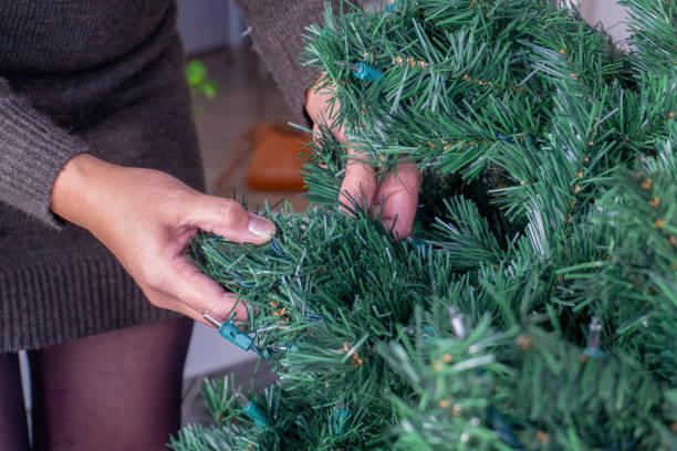 istock Hands unravelling an artificial Christmas tree without ornaments. 1131731164