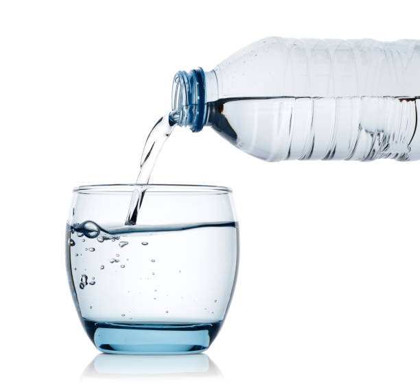 drinking water is poured into glass from bottle - water bottle cold purified water imagens e fotografias de stock