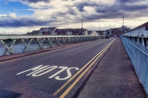 Waterloo Bridge (Black Bridge) over the River Ness from Merkinch, Inverness, Scotland River Ness, Inverness, Scotland, UK - Feb 17 2019:  The River Ness is 6 miles long.  Flowing from the northern end of Loch Ness to Inverness, then into the Beauly Firth.  It’s Scottish Gaelic name ‘Inbhir Nis’, means "Mouth of the Ness".  Seven bridges span the Ness.  Here we see ‘Waterloo bridge’.  It is locally known as the ‘Black Bridge”.  This is due to it’s original wooden structure built in 1808, that was black in colour.  This metal bridge replaced it in 1896 and is of iron construction.  The view is from the Merkinch area of the city, looking towards the cars crossing. waterloo bridge stock pictures, royalty-free photos & images