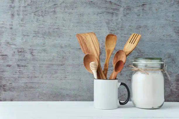 Photo of Kitchen utensils in ceramic cup on a gray background, copy space