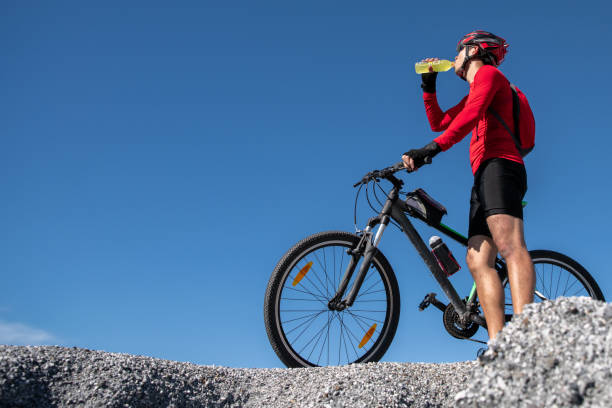 istock Cyclist resting and drinking isotonic drink. Backlight, sunny summer day. Extreme mountain bike sport athlete man riding outdoors lifestyle trail. 1131740407