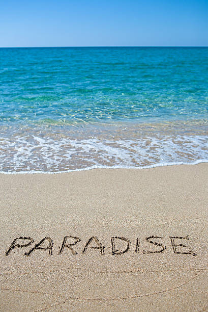 Paradise written on the sand stock photo