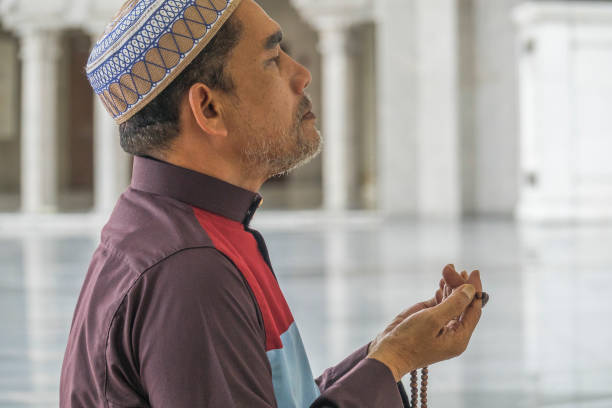istock Side View Of Mature Man Praying While Kneeling At Mosque 1131750183