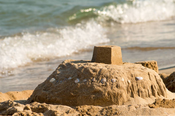 istock Sand castle on the seashore and a soft blue sea wave. 1131751908