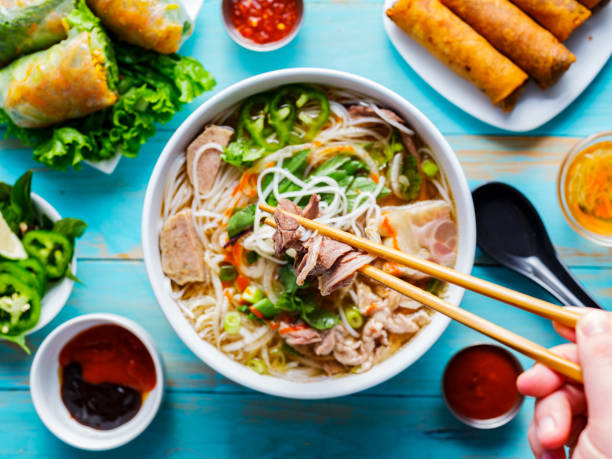 eating colorful vietnamese pho bo with chopsticks eating colorful vietnamese pho bo with chopsticks from top down view noodle soup photos stock pictures, royalty-free photos & images